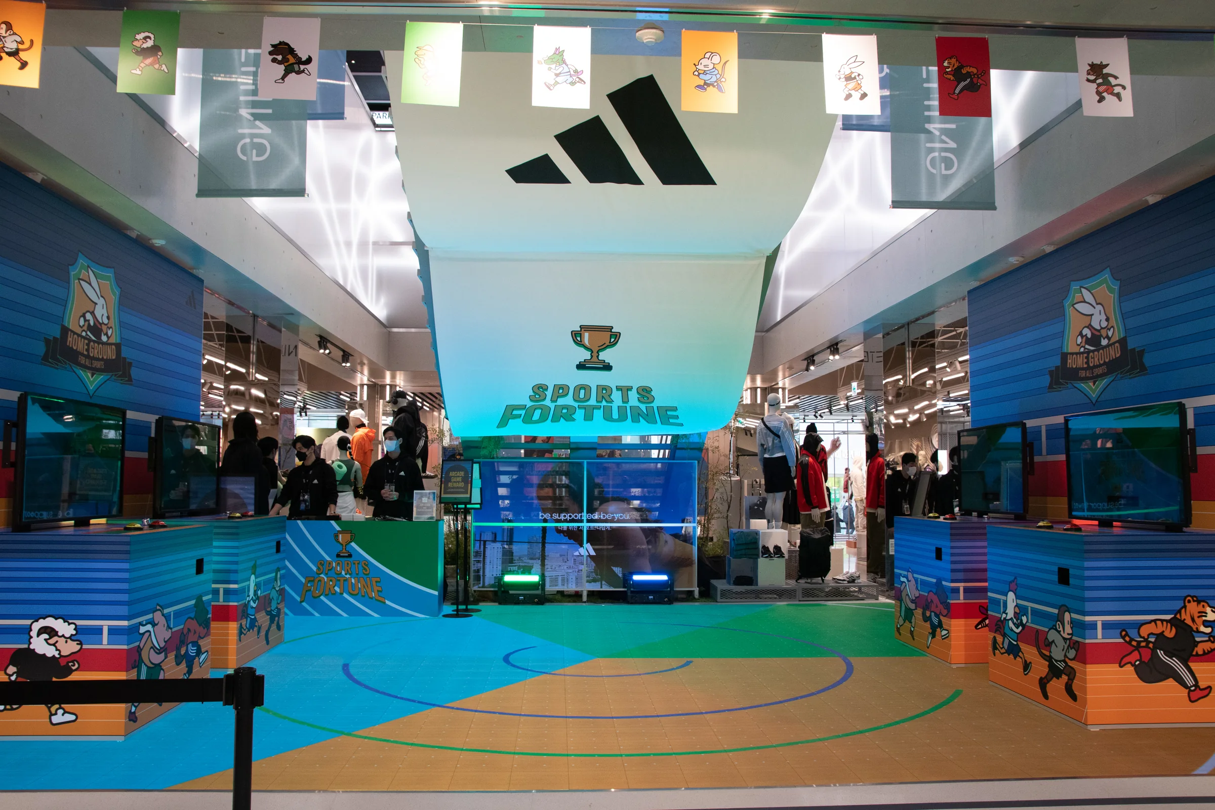 Visitors walk between the arcade machines and an LED floor showing a basketball court.