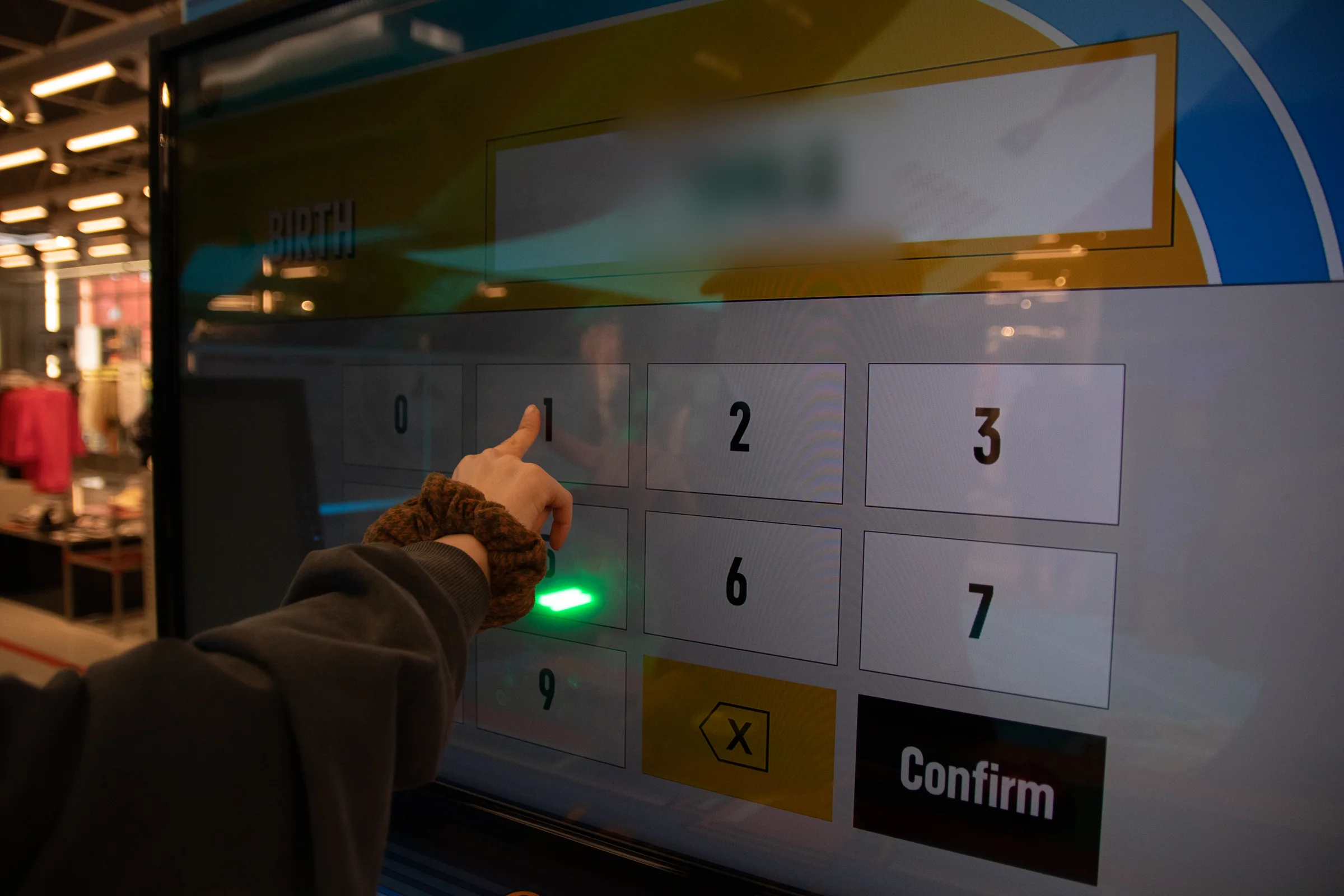 A hand enters a birth date on the numeric keypad.