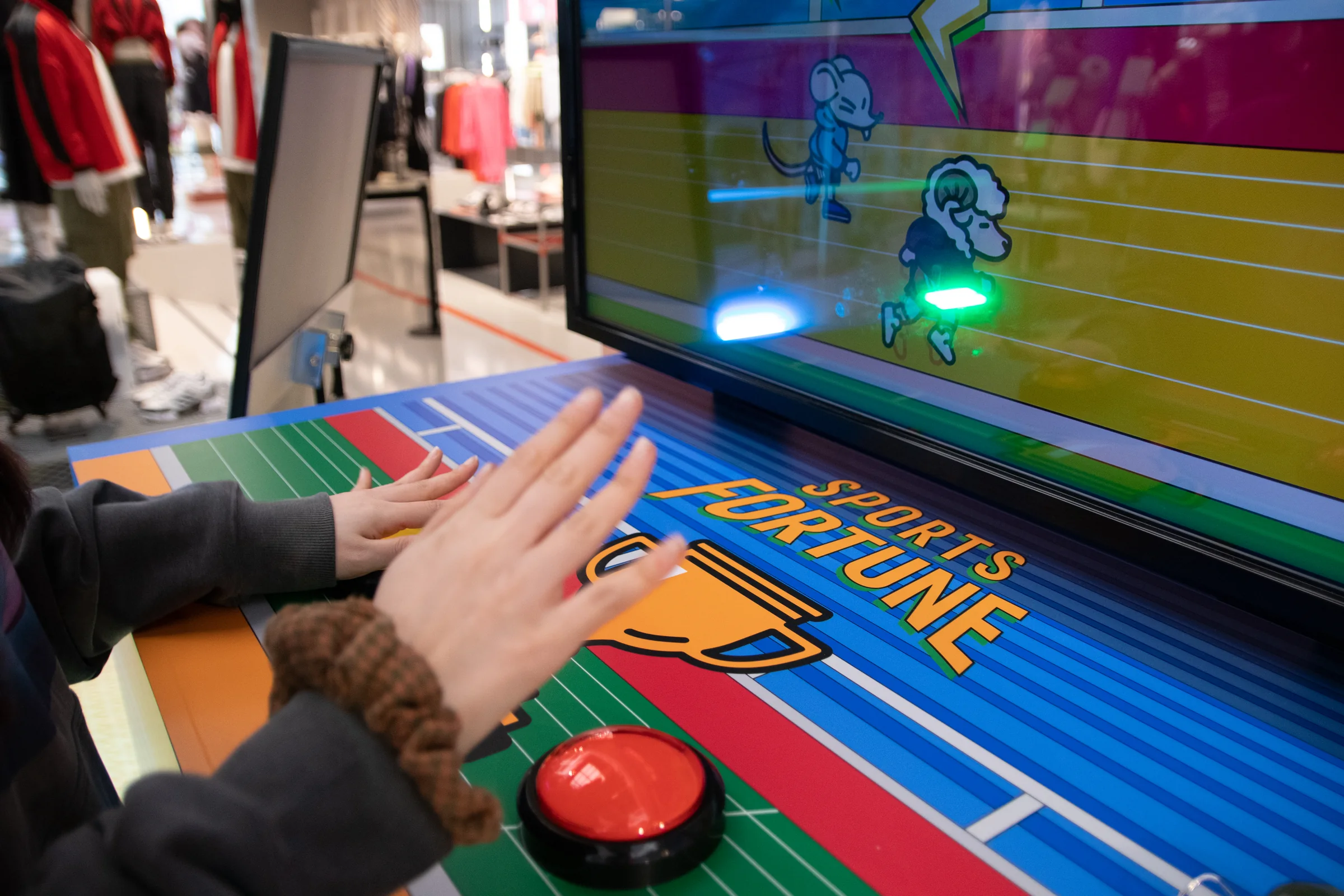 A hand presses a red button while the participant watches the race.