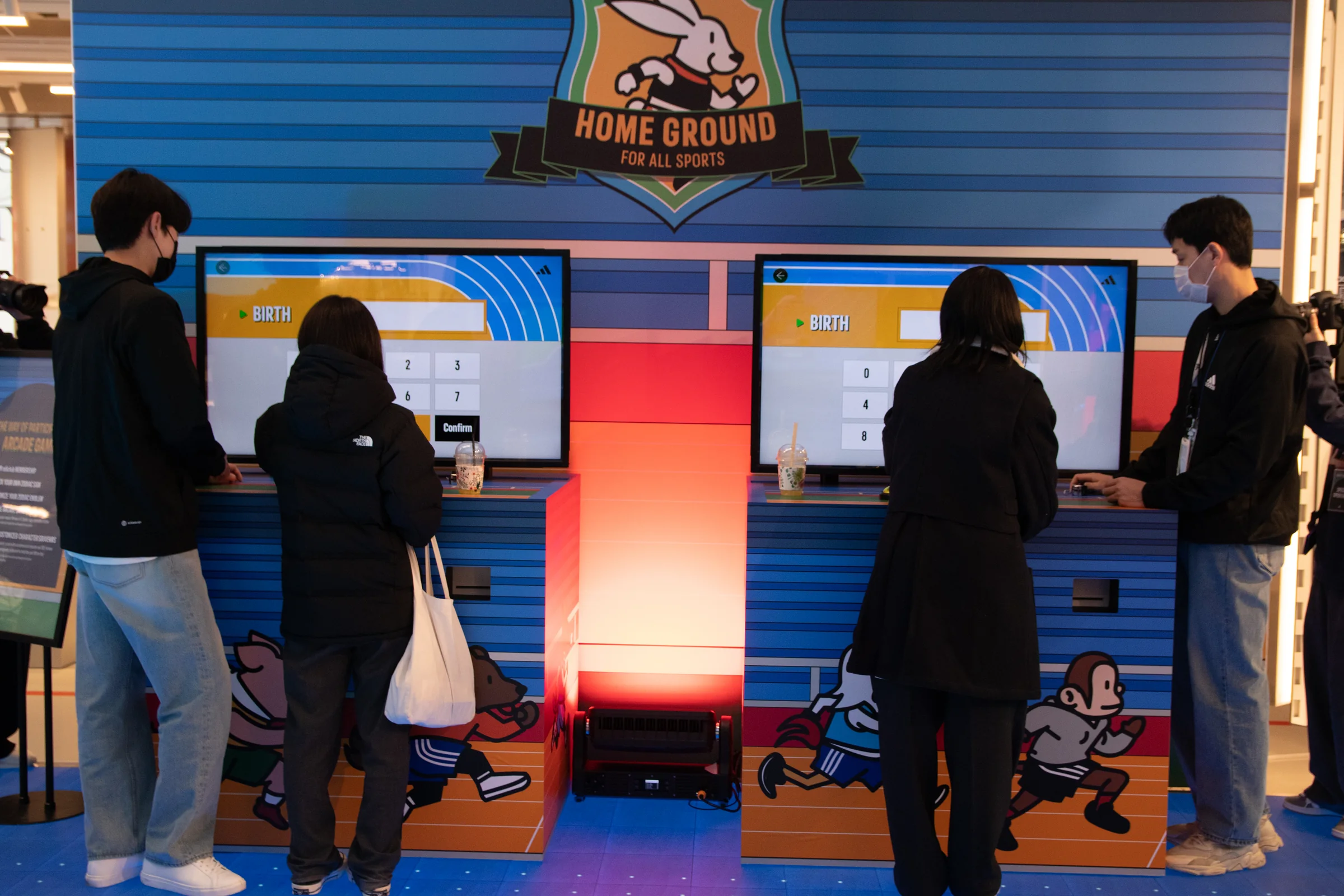 Participants at two machines beneath the HOME GROUND badge