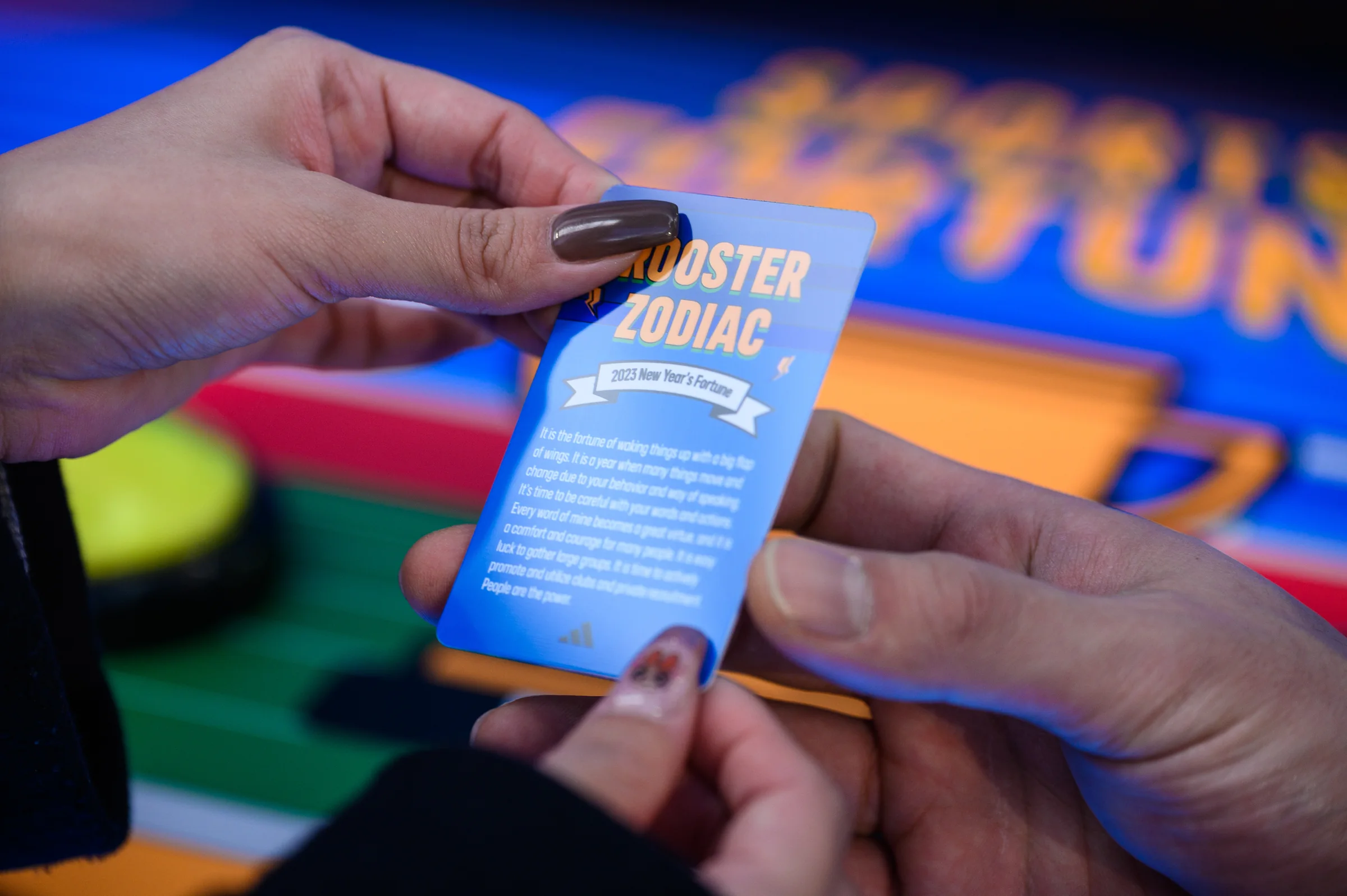 The back of a fortune card held in two hands, showing ROOSTER ZODIAC and a 2023 fortune