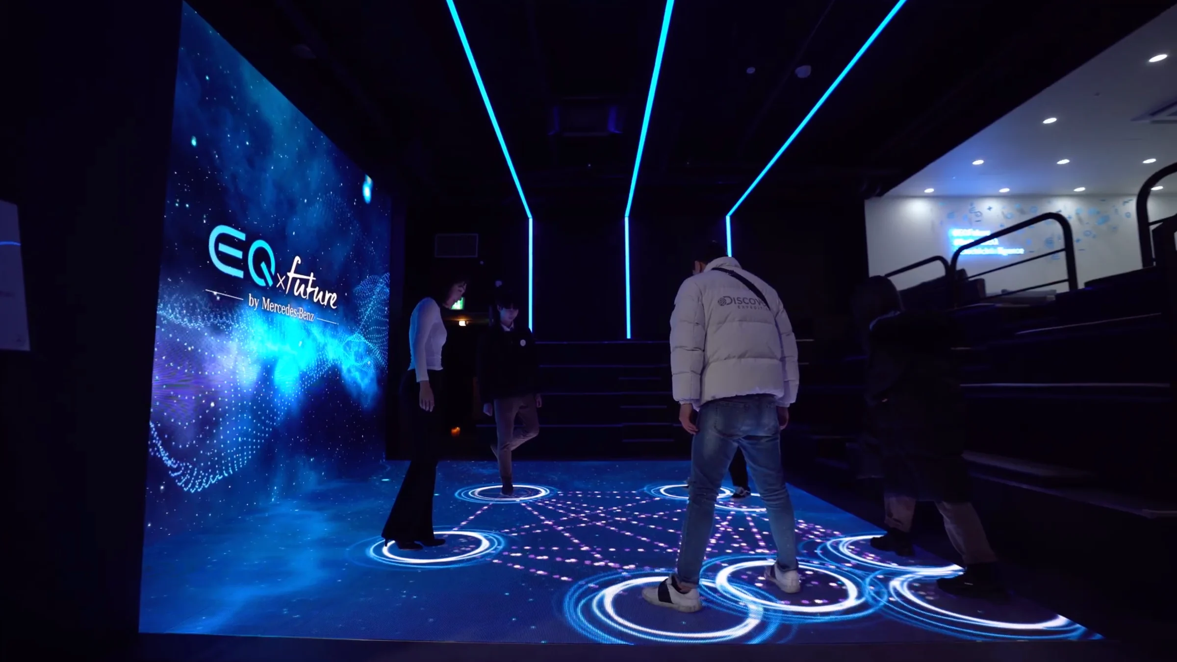 Visitors standing on an LED floor filled with circles of light