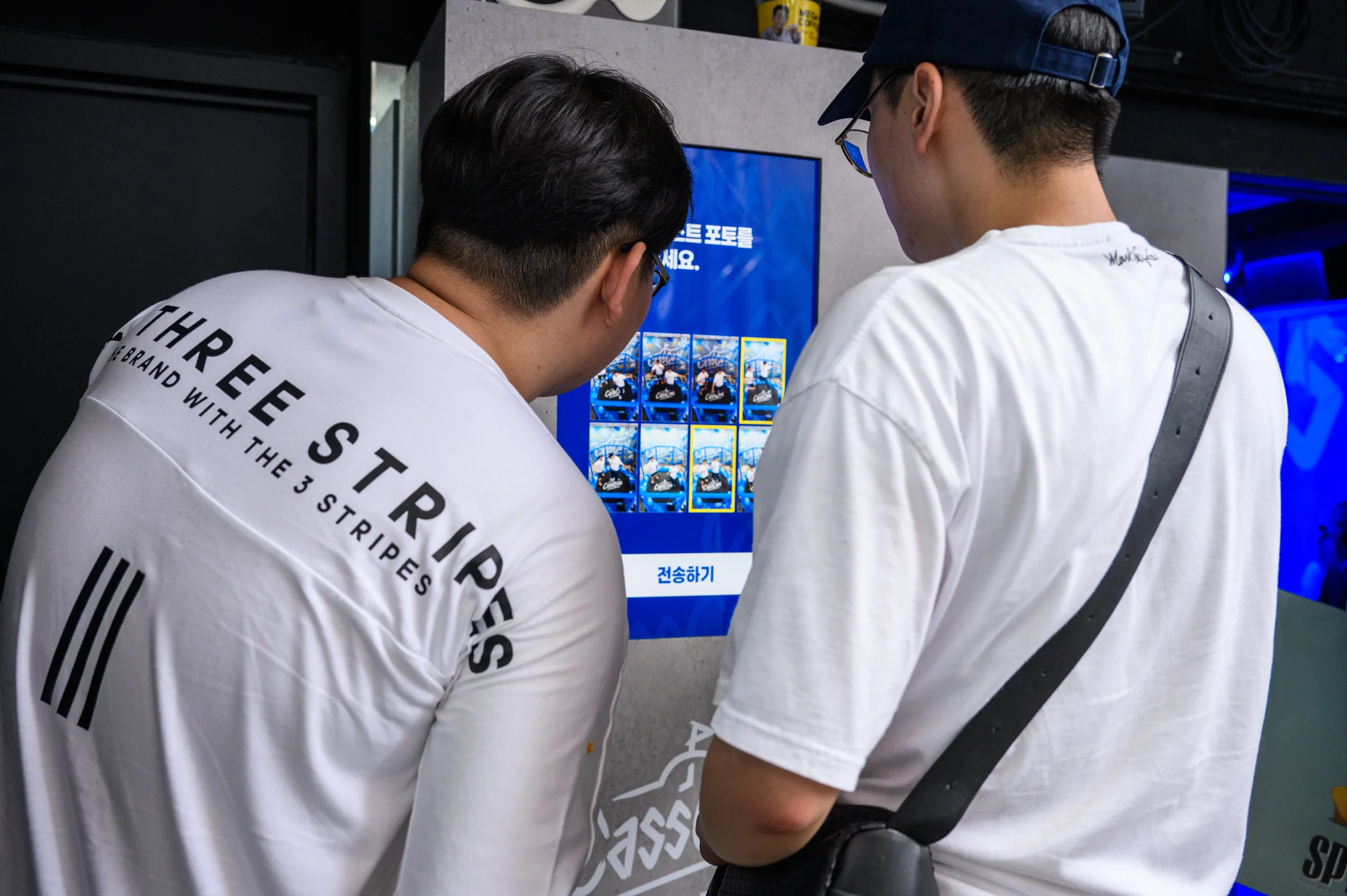 벽의 세로 키오스크에서 사진을 고르는 두 관람객