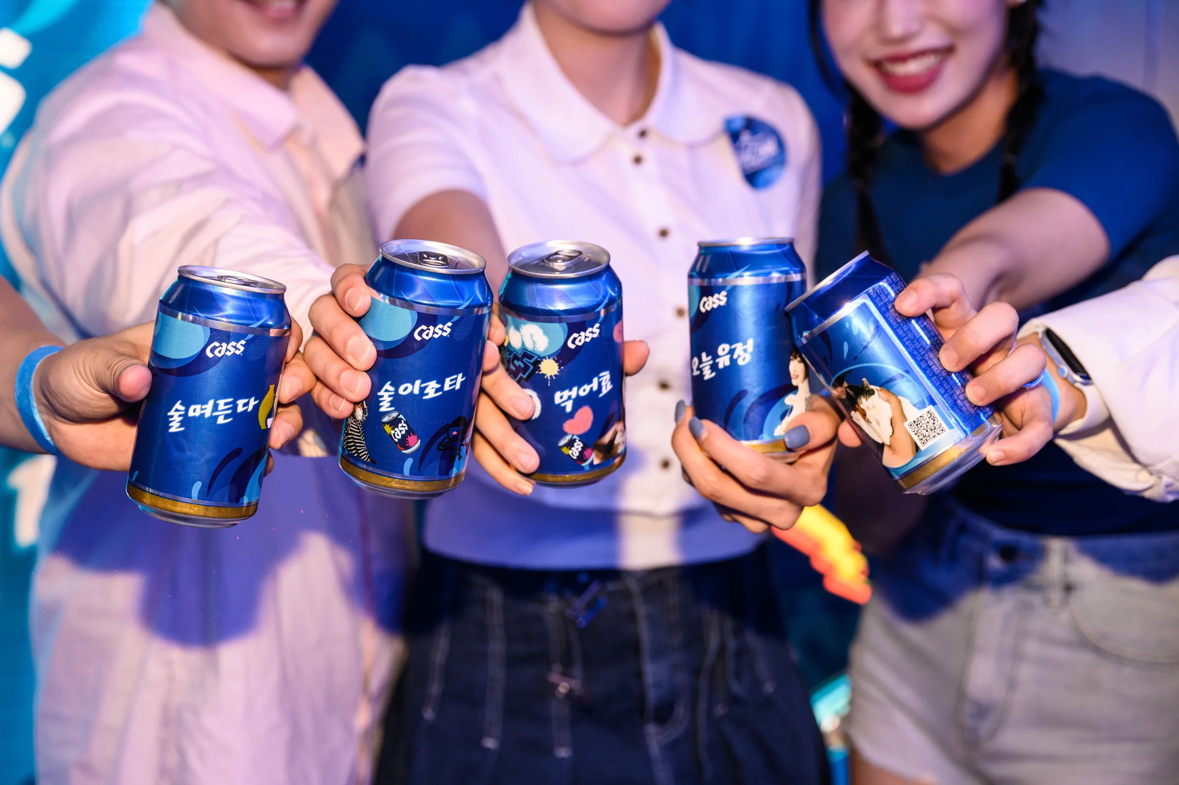 라벨을 두른 카스 캔으로 건배하는 관람객들