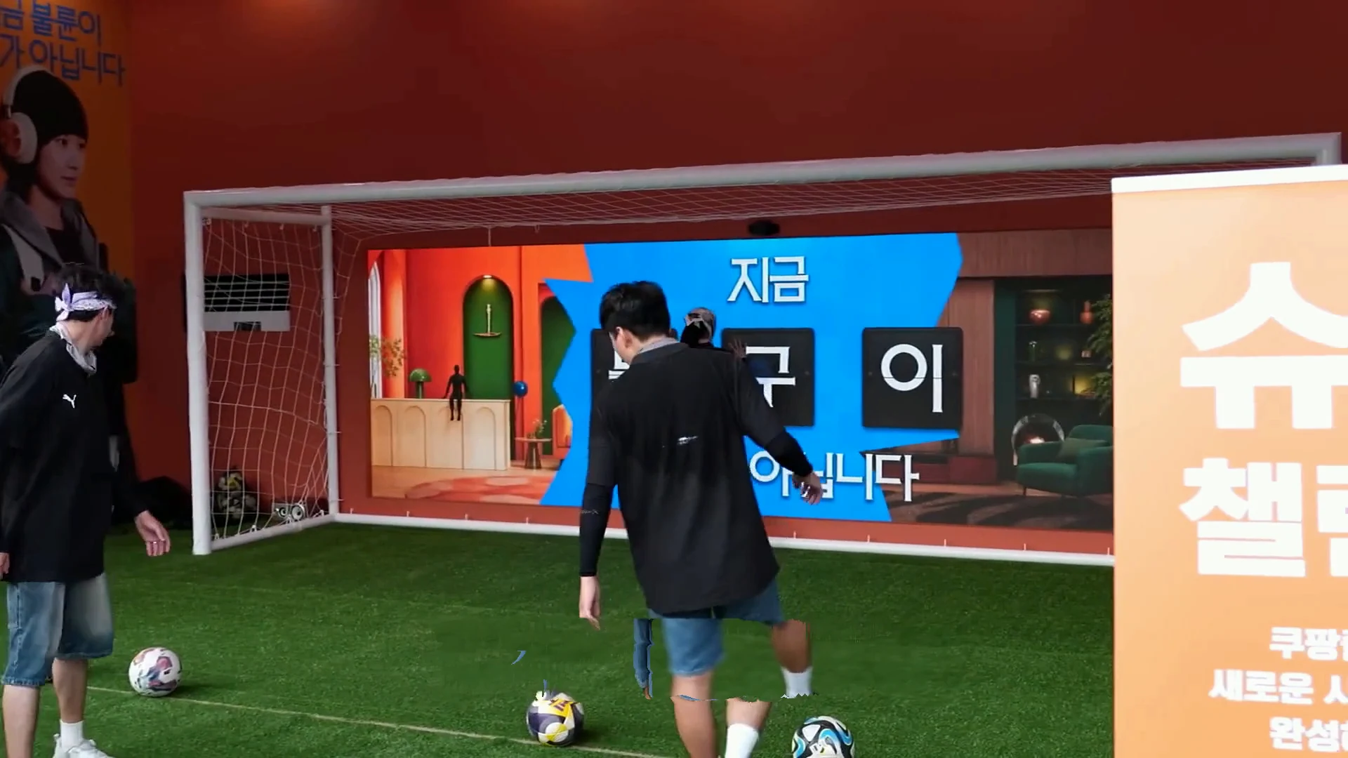 검은 옷의 참가자가 LED 골대를 향해 공을 차고 있다.
