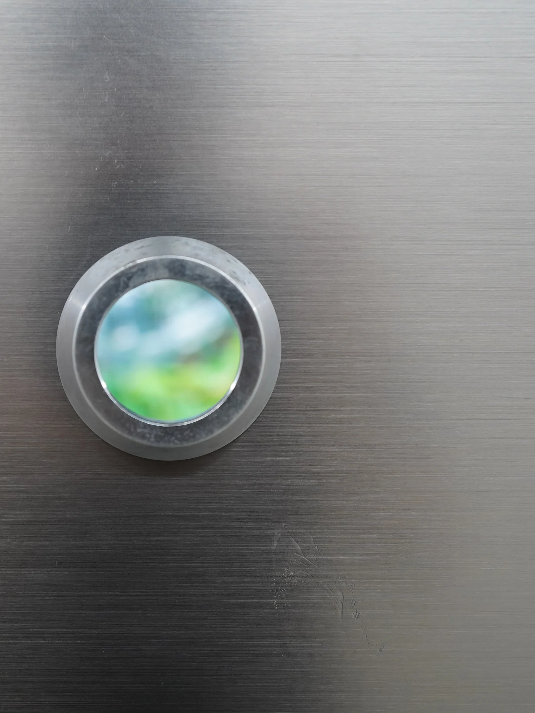 Close-up of a metal-ringed viewing hole, with a scene visible inside