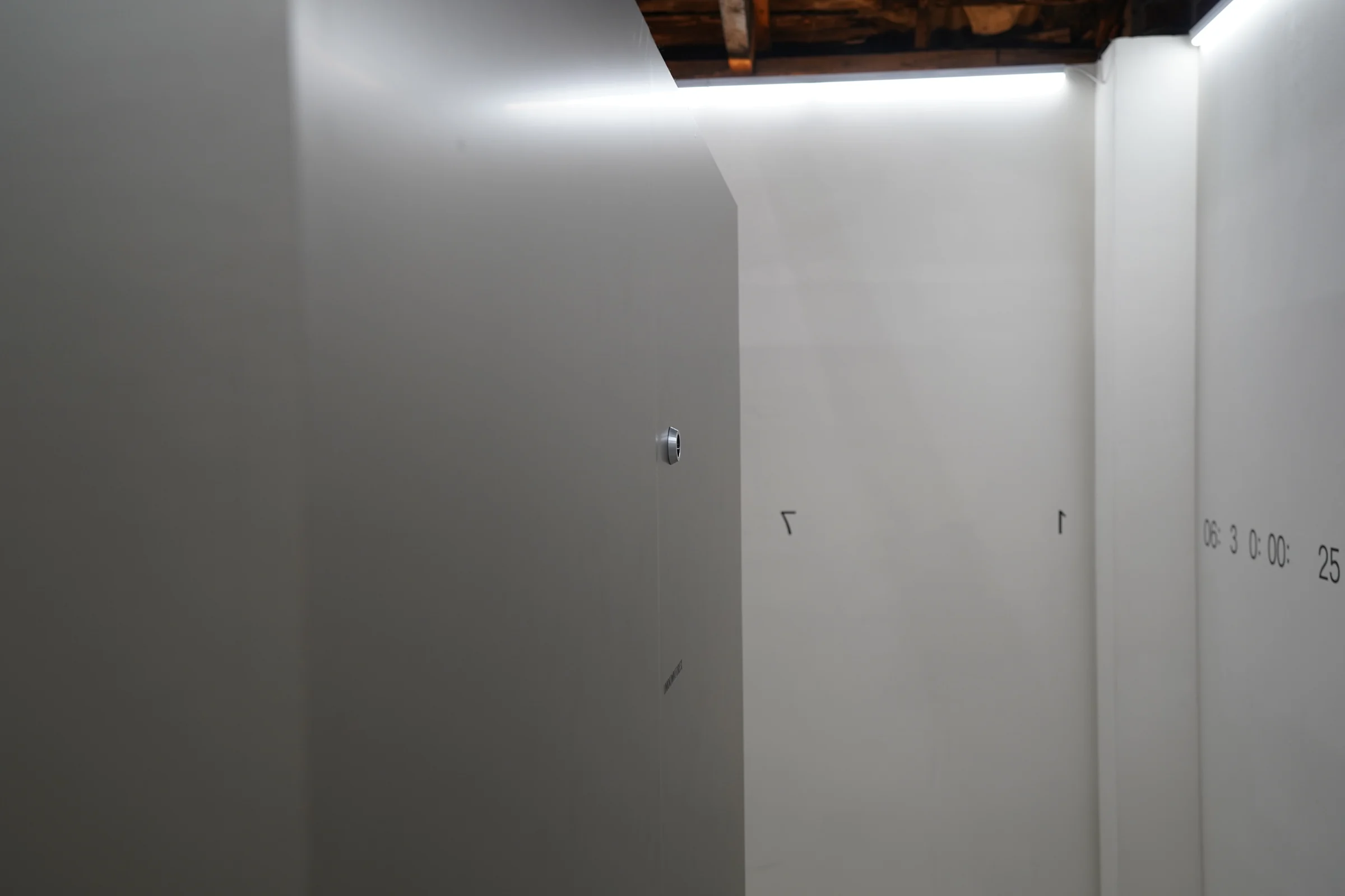 A white room marked with timecode numbers and the corner of the metal cube