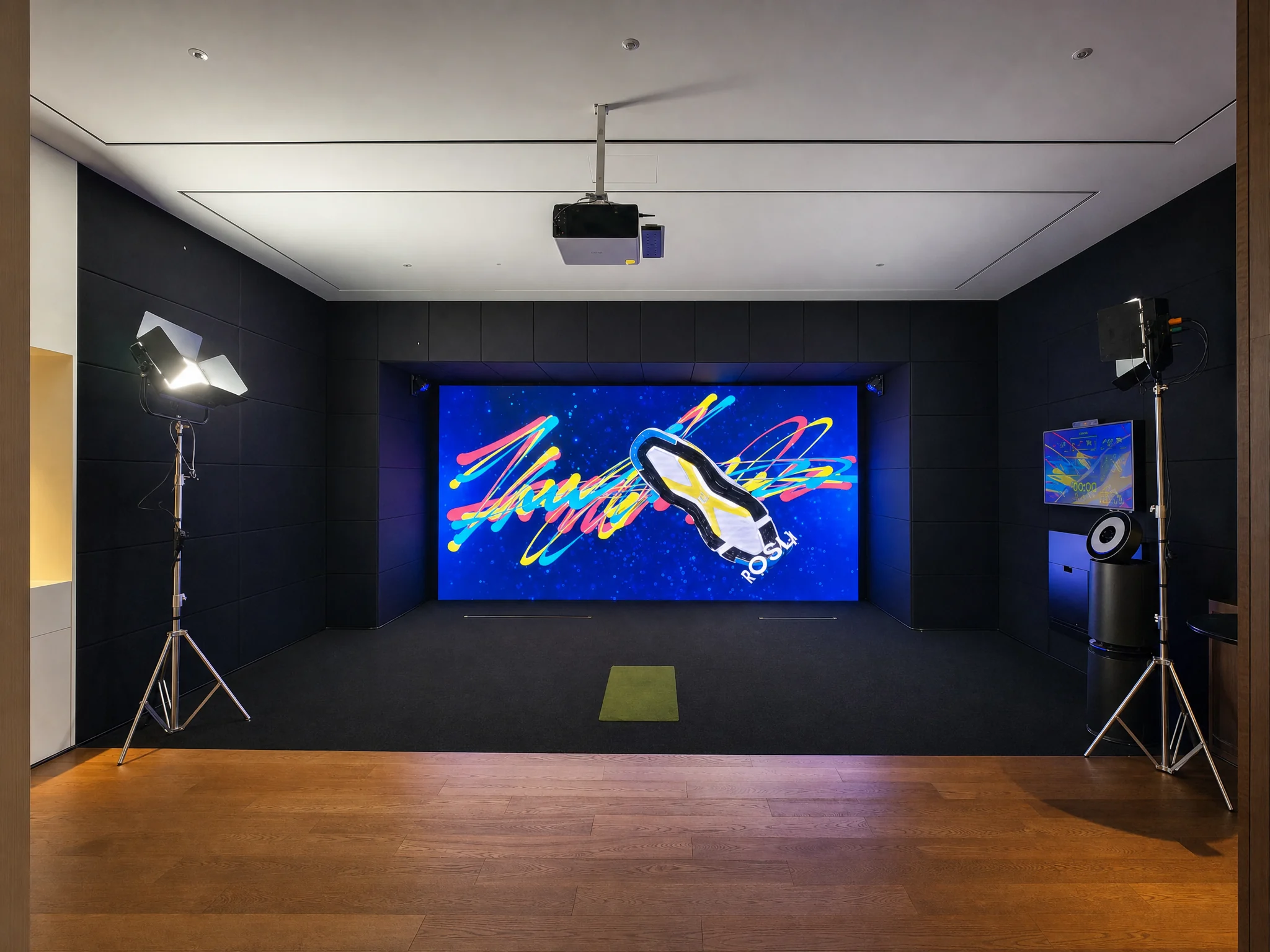 ラウンジの床の先に開く暗いフォトゾーン。天井のプロジェクター、左右の照明、奥のLEDウォール。