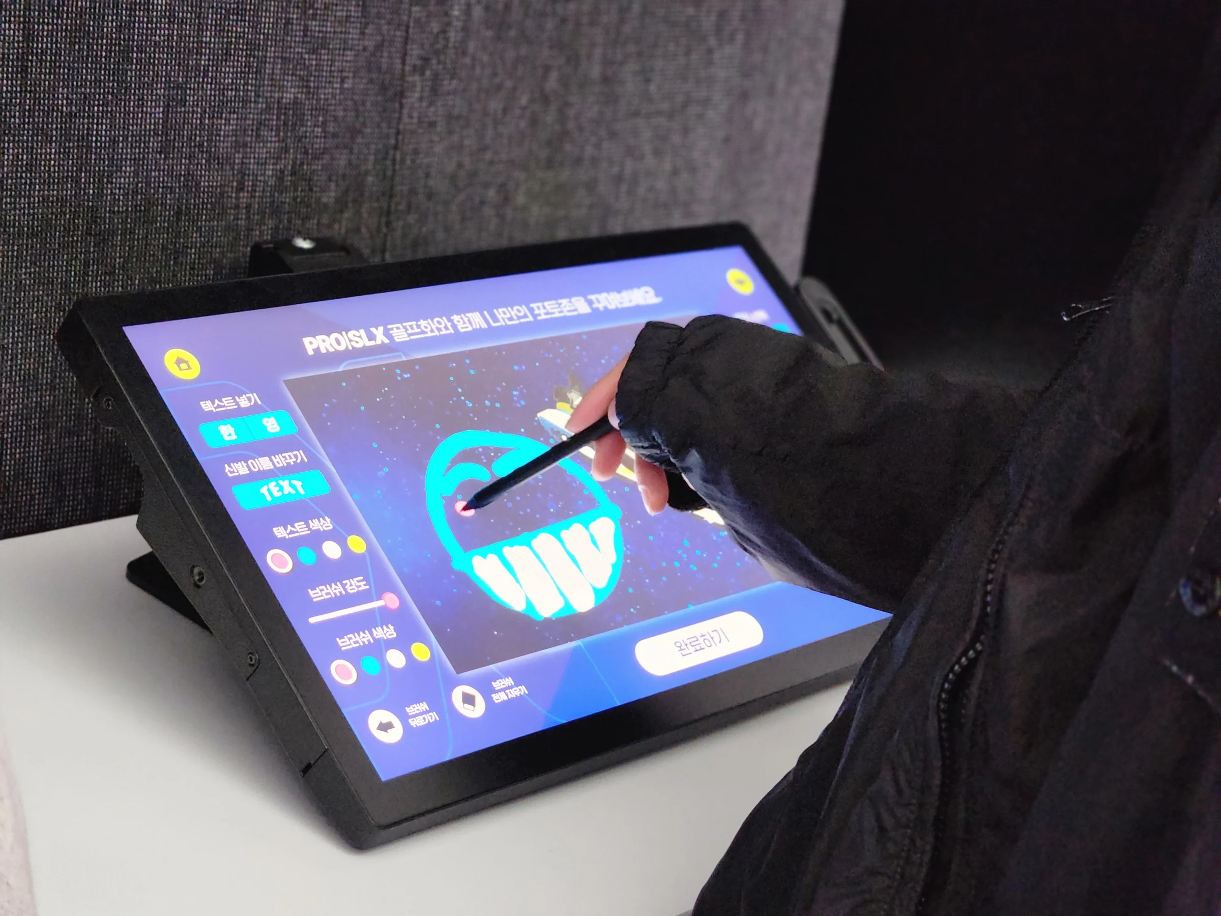 タブレット画面の靴に、ペンで色の線を描く手。