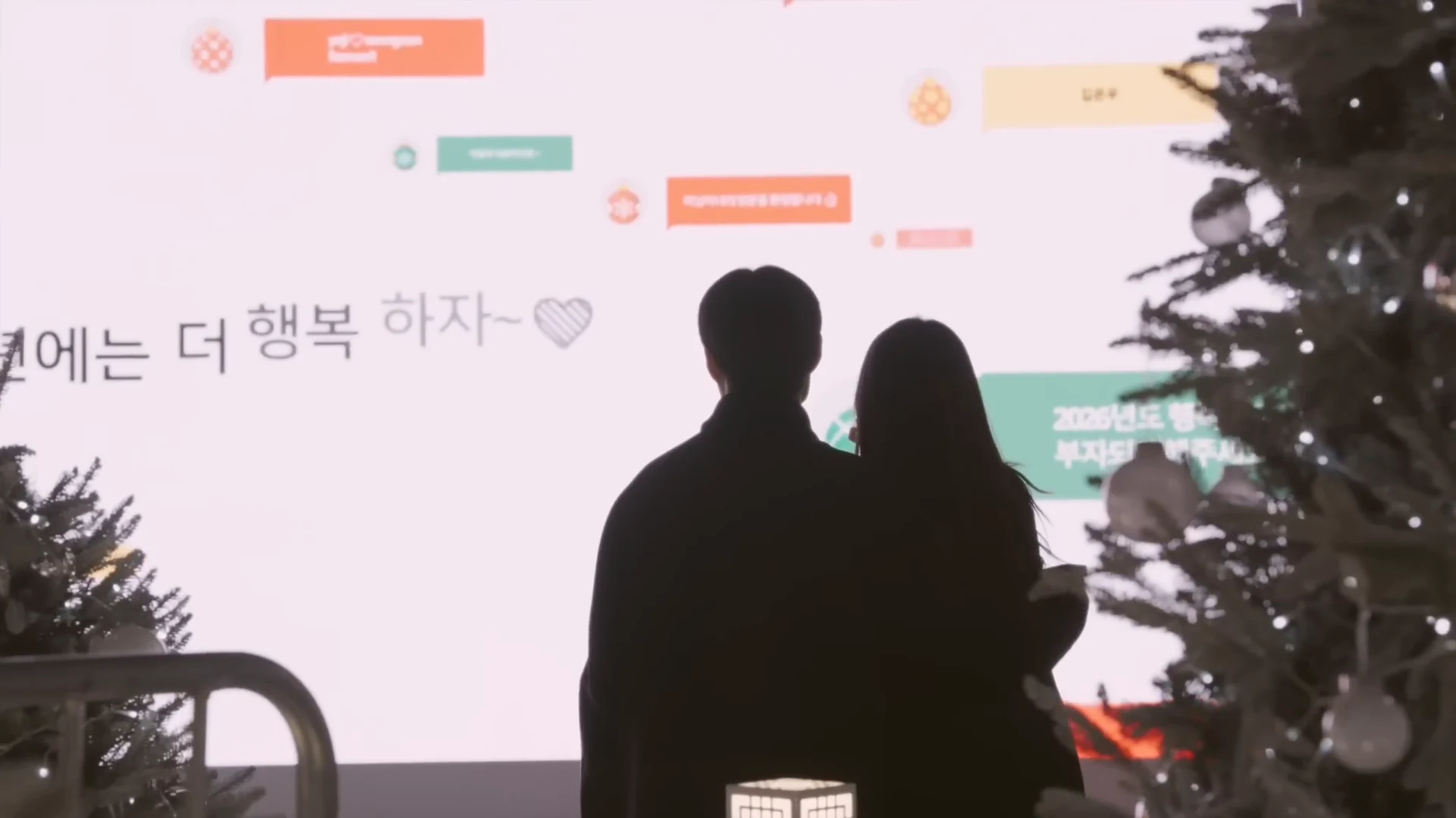 흰 메시지 벽 앞에 선 두 사람의 실루엣