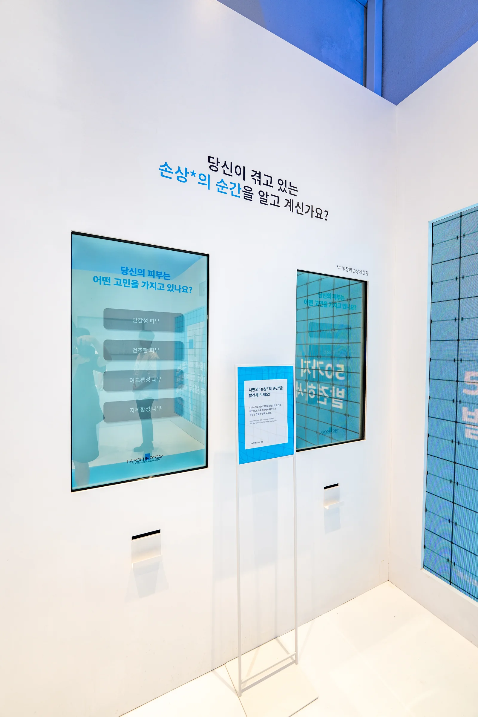 흰 벽에 설치된 터치 화면 두 대와 화면 아래의 영수증 출구