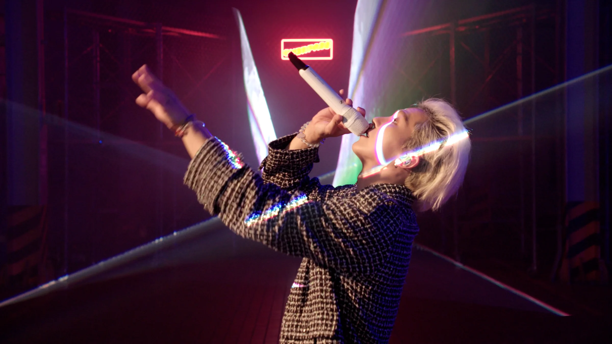 MINO singing into a microphone as laser beams cross his face
