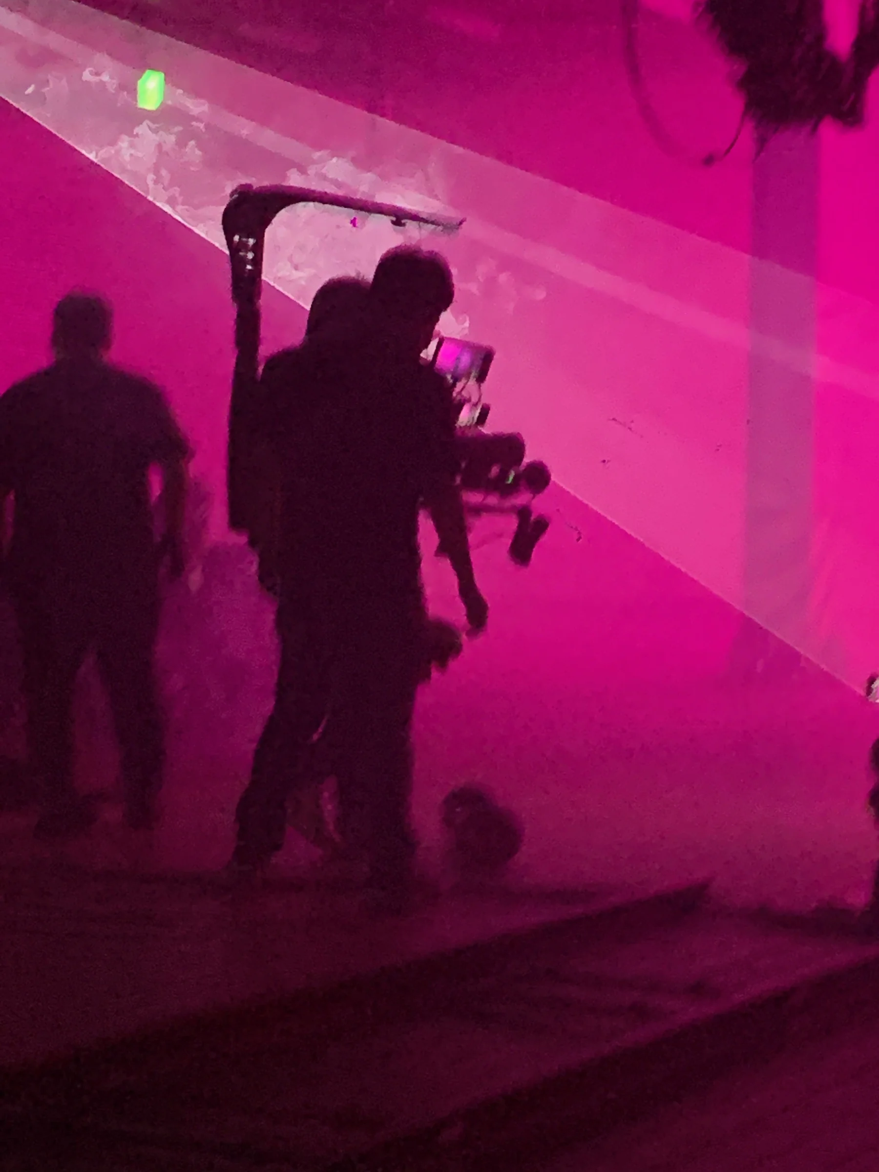 Silhouettes of the camera crew in pink laser light