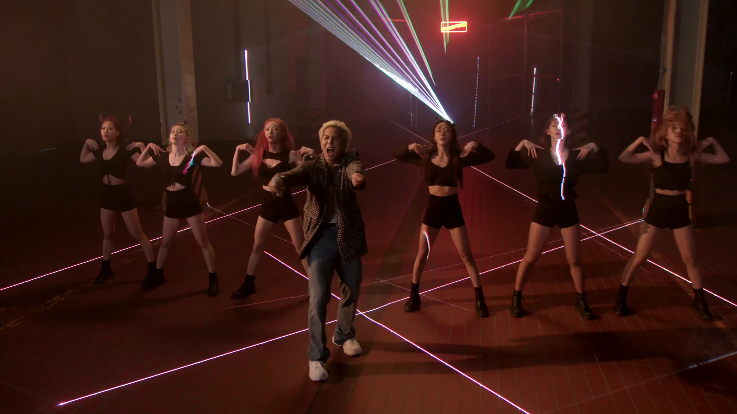 MINO and dancers standing in a line beneath the beams