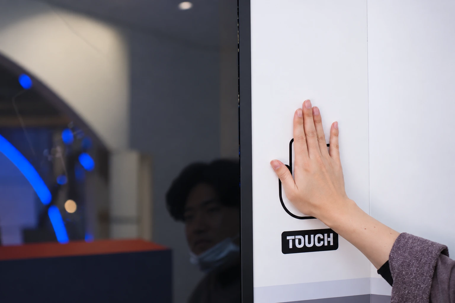 모니터 옆 흰 패널의 손바닥 표시에 손을 댄 모습