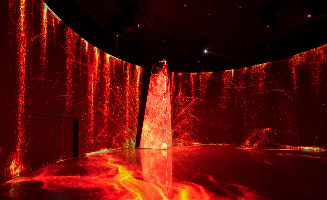 A circular hall filled with red imagery on its walls and floor, and a glowing tower