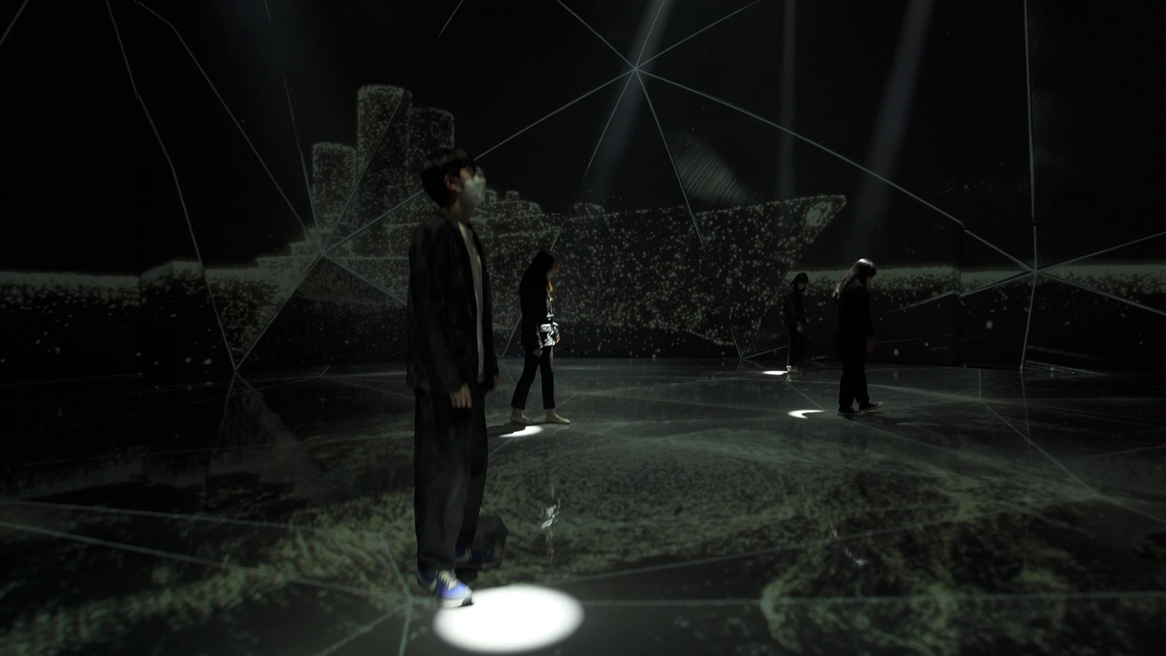 A large circle of light beneath a standing visitor, with smaller lights beneath visitors behind