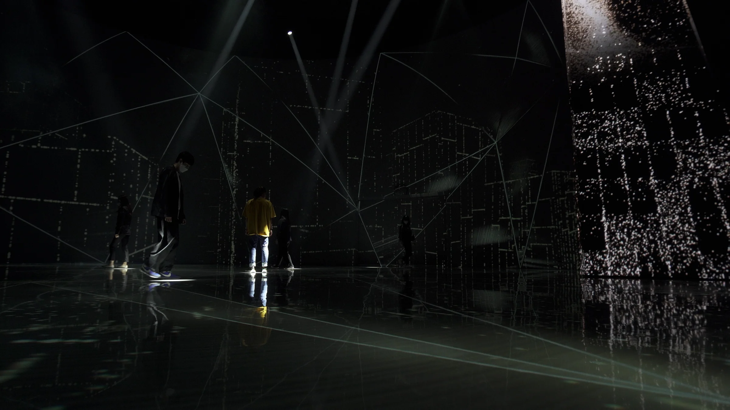 Visitors walking beside an ore-shaped tower, with light at their feet