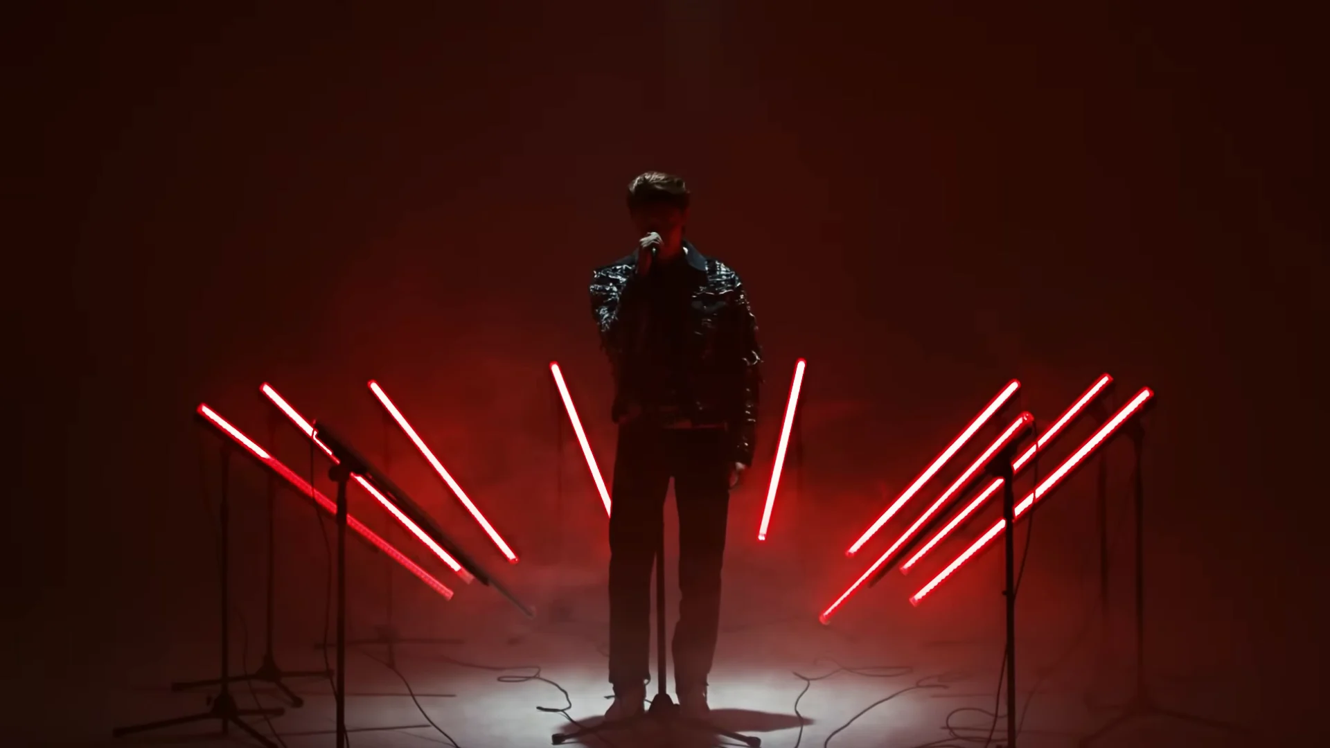 The performer in red backlight, with red bars on both sides